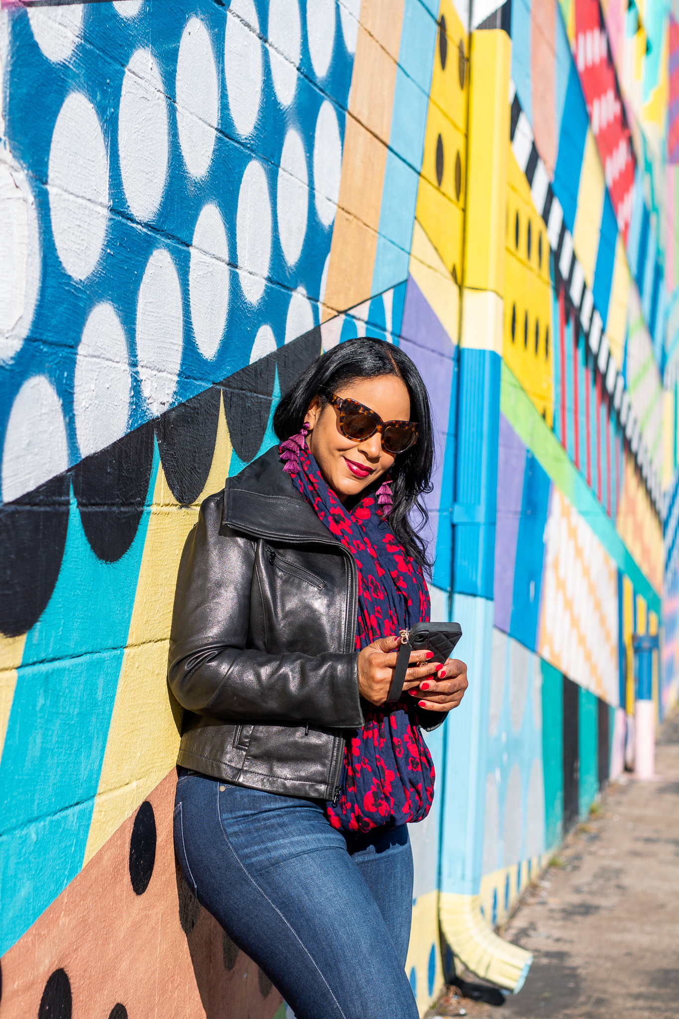 Back into Books + What Are You Reading? Pictured: woman standing against decorative wall reading on her cell phone in Nashville, TN